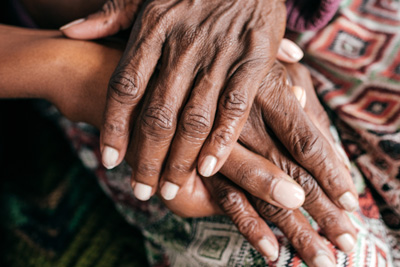 close-up of hands of older adult help by hands of younger adult
