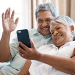 Older adult couple video chatting with family on a cell phone.